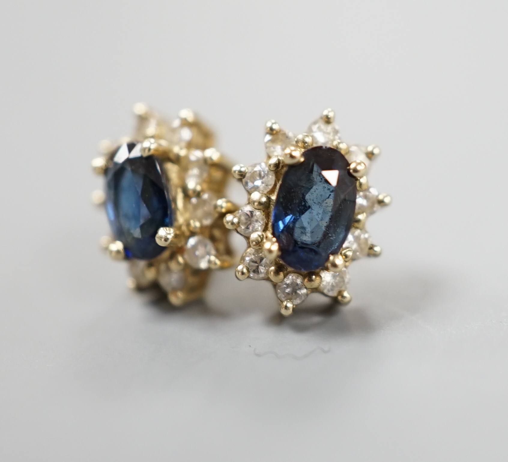 A pair of modern 9ct gold, sapphire and diamond chip set oval cluster earrings, gross 1.3 grams.